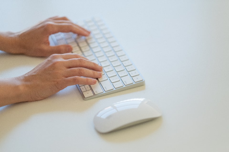 Close-up of hands typing on a minimalist keyboard